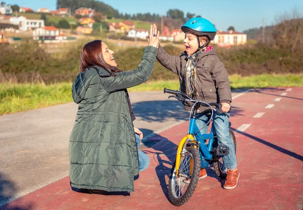 Mother and son giving five by success riding bicycle — Stock Photo, Image