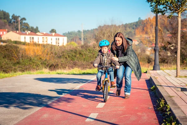 Mother teaching son to ride a bike in cycleway — Stock Photo, Image