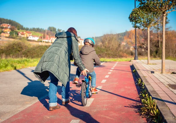 Mother teaching son to ride a bike in cycleway — Stock Photo, Image