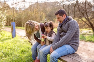 Erkek ve kadın küçük kız bankta oturan ile oynarken