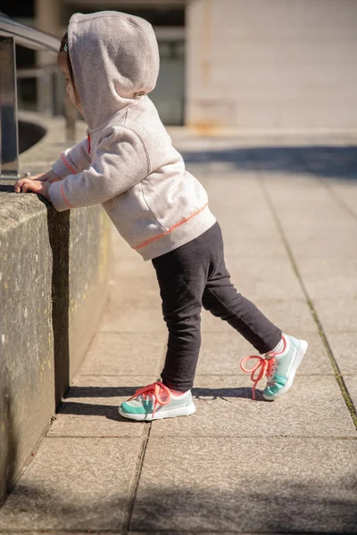 Little girl with sneakers and hoodie warming outdoors — Stock Photo, Image