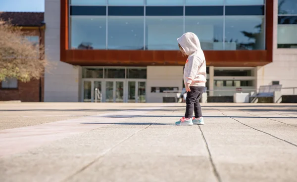 Little girl with hoodie looking her sneakers outdoors — Stock Photo, Image