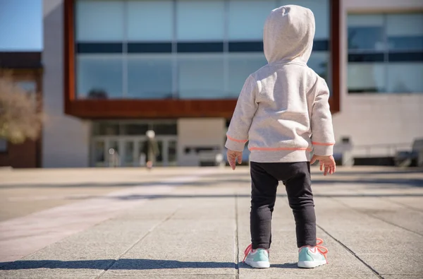 Little girl with sneakers and hoodie standing outdoors — Stock Photo, Image