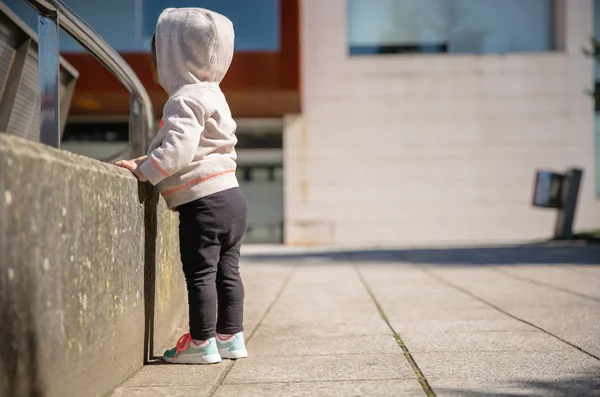 Bambina con sneakers e felpa con cappuccio in piedi all'aperto — Foto Stock