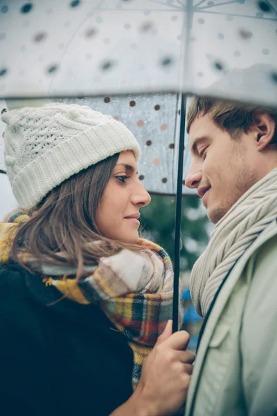 Young couple looking at each other under umbrella outdoors — Stock Photo, Image