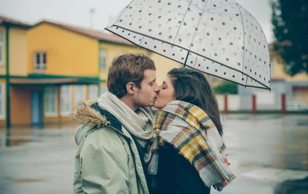 Mladý pár líbání venku pod střechou v deštivý den — Stock fotografie