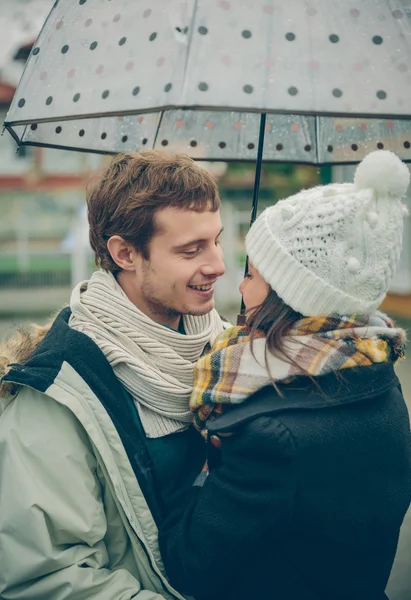 Young couple embracing outdoors under umbrella in a rainy day