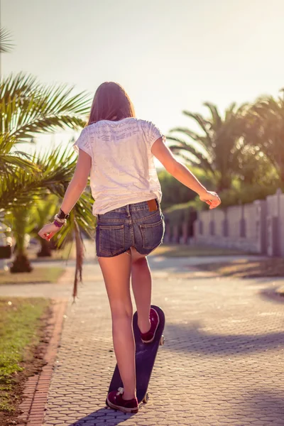 Back view of girl riding in a skateboard outdoors on summer — Stock Photo, Image