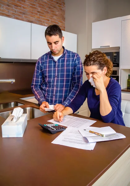 Unemployed husband reviewing the bills and wife crying by debts