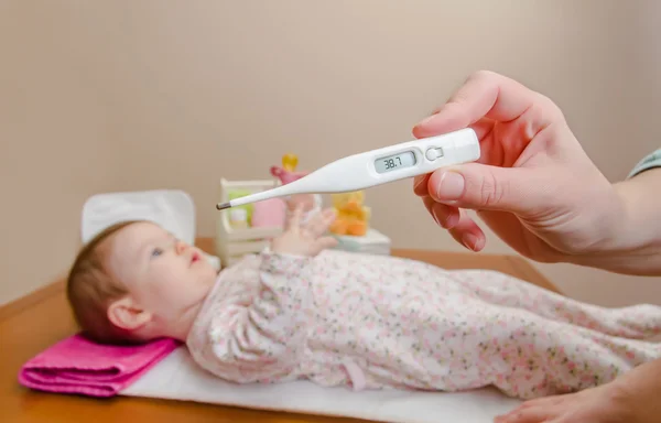 Mãe mão medir a temperatura do bebê no termômetro — Fotografia de Stock
