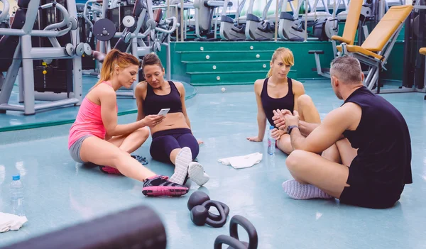 Frauen suchen Smartphone und befreundete Paare unterhalten sich im Fitnessstudio — Stockfoto