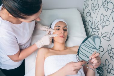 Kadın Doktor hastaya yüz bölgeleri bir tedavi için gösterilen
