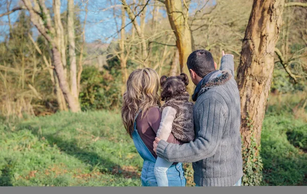 Pareja con su pequeña hija disfrutando del paisaje forestal —  Fotos de Stock