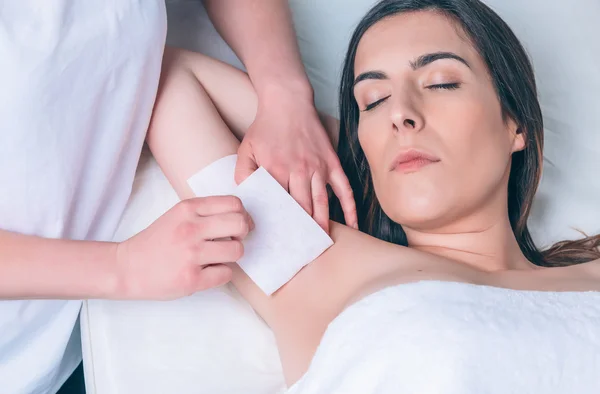 Beautician hands doing depilation in woman armpit with wax strip — Stock Photo, Image