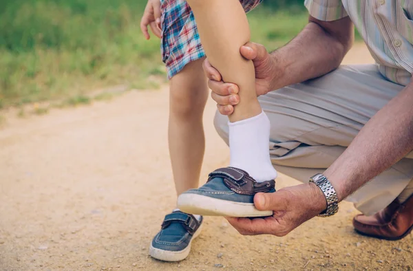 Grandfather putting shoe to his grandson outdoors — Stock Photo, Image