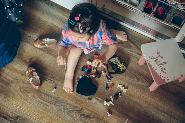 Menina bebê brincando com grampos de cabelo sentado no chão — Fotografia de Stock