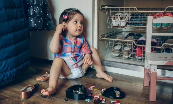 Baby girl playing with hair clips sitting in the floor — Stock Photo, Image