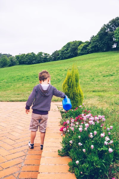 Gelukkige jongen drenken bloemen in de tuin — Stockfoto
