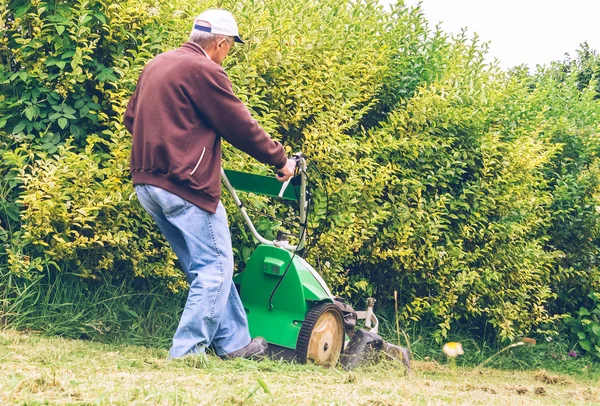 Hombre mayor cortando el césped con cortacésped — Foto de Stock