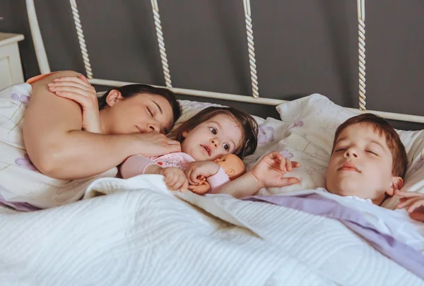 Menina abraçando boneca deitada sobre a cama — Fotografia de Stock