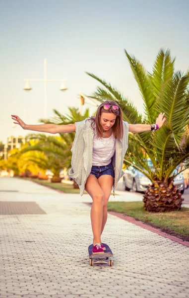 Ung pige ridning i et skateboard udendørs om sommeren - Stock-foto