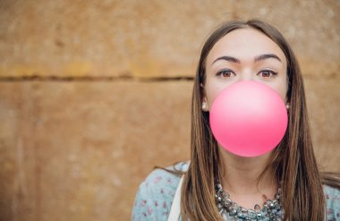 Young teenage girl blowing pink bubble gum clipart