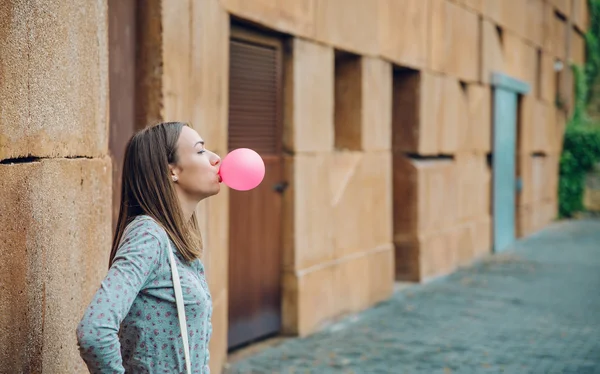 Giovane ragazza adolescente che soffia gomma da masticare rosa — Foto Stock