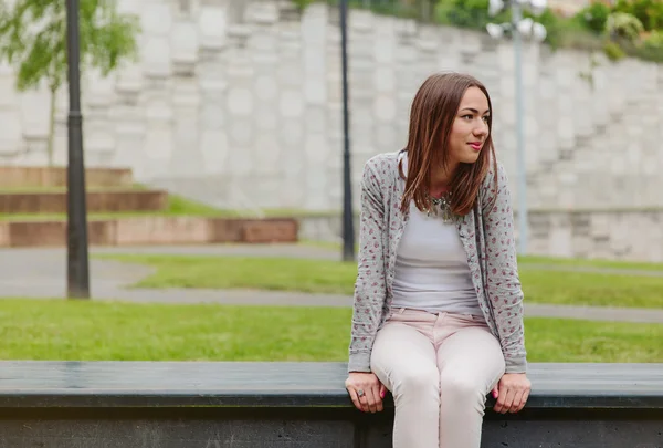 Красивая молодая женщина сидит на скамейке в парке — стоковое фото