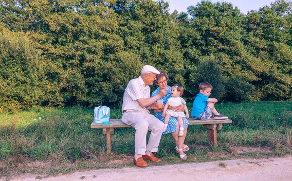 Старший чоловік годує дитину, сидячи на лавці — стокове фото