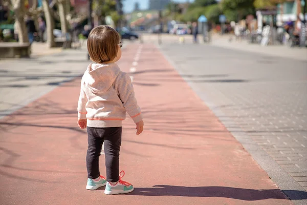 Little girl with sneakers standing over a city runway — Stock Photo, Image