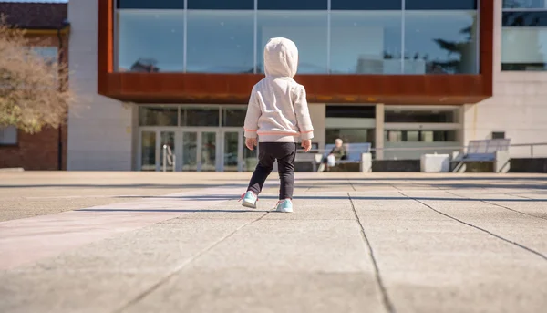 Little girl with sneakers and hoodie standing outdoors — Stock Photo, Image