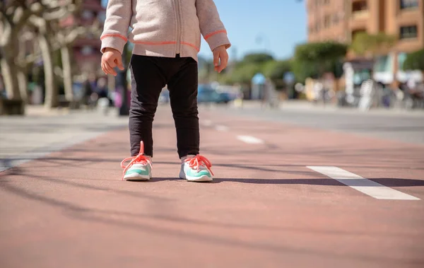 Bambina con scarpe da ginnastica e leggins in piedi sopra una pista di città — Foto Stock