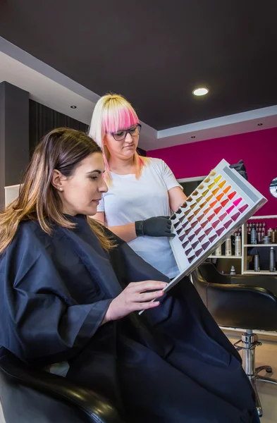 Mulher olhando com cabeleireiro uma paleta de tintura de cabelo — Fotografia de Stock