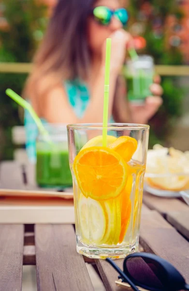 Наповнені коктейлі з фруктовою водою та жінка, що п'є зелену смужку — стокове фото