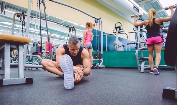 Uomo stretching e donne che fanno esercizi manubri in palestra — Foto Stock