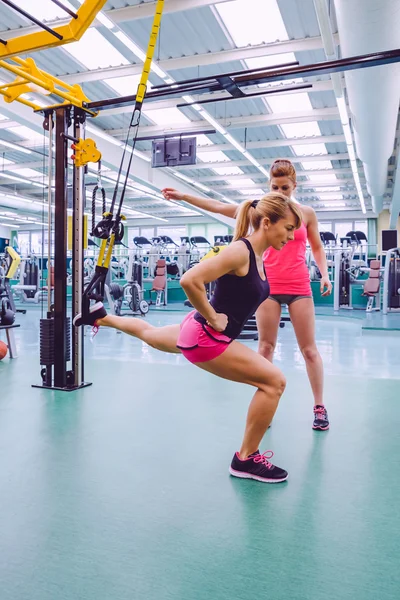 Personal trainer teaching to woman in suspension training — Stock Photo, Image