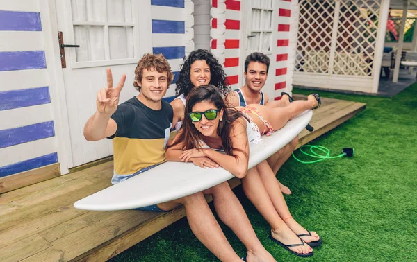 Young friends holding woman on top of surfboard — Stock Photo, Image