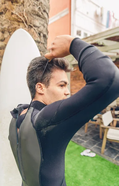 Young surfer man with surfboard closing wetsuit — Stock Photo, Image