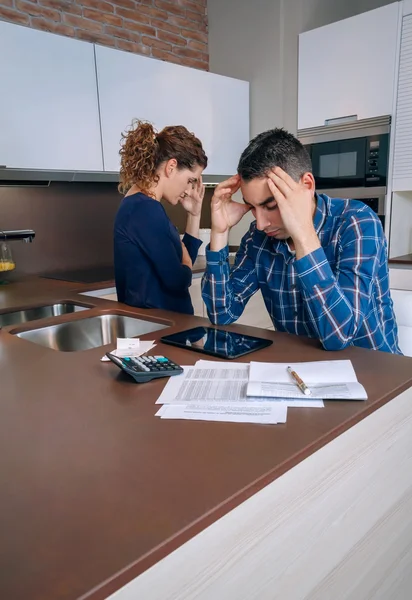 Отчаянная молодая пара с долгами пересматривает свои счета — стоковое фото