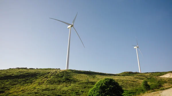 Turbine eoliche che generano elettricità su sfondo cielo blu — Foto Stock