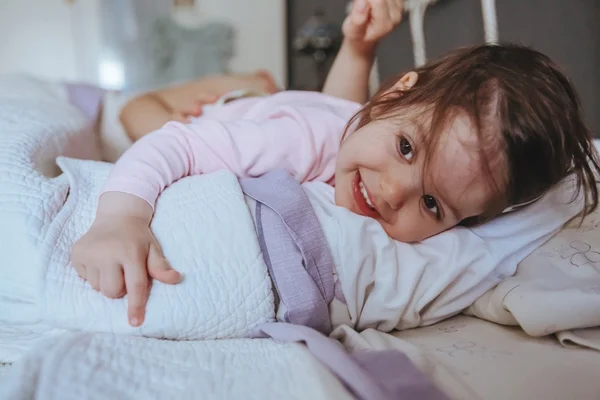 Little girl smiling lying over the bed — Stock Photo, Image