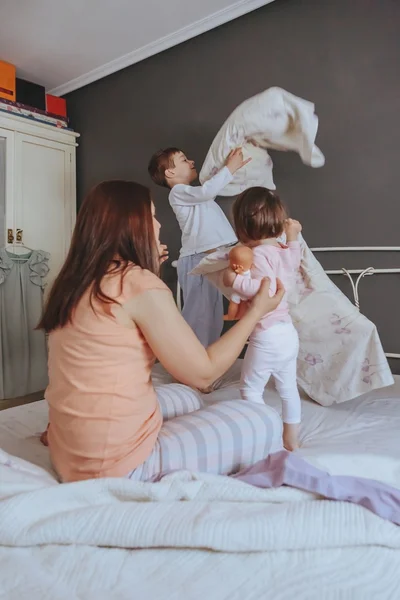 Расслабленные мать и сыновья играют над кроватью — стоковое фото