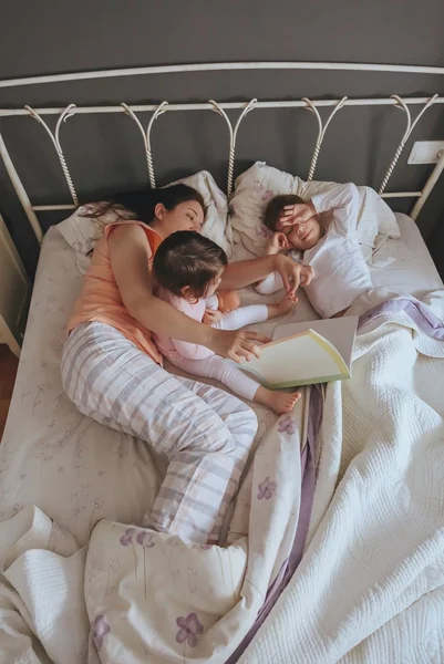 Madre leyendo libro a sus hijos en la cama —  Fotos de Stock