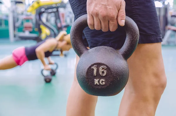 Hombre sosteniendo kettlebell y mujer haciendo flexiones en kettlebells —  Fotos de Stock