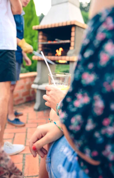 Woman holding lemonade glass and friends cooking in barbecue — Stock Photo, Image