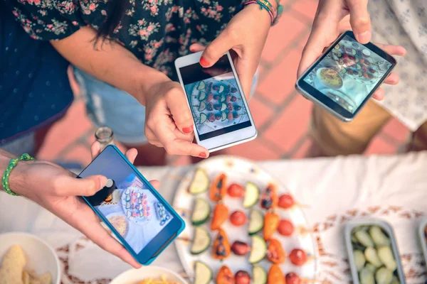 Молодые руки фотографируют со смартфонами на овощные шампуры — стоковое фото