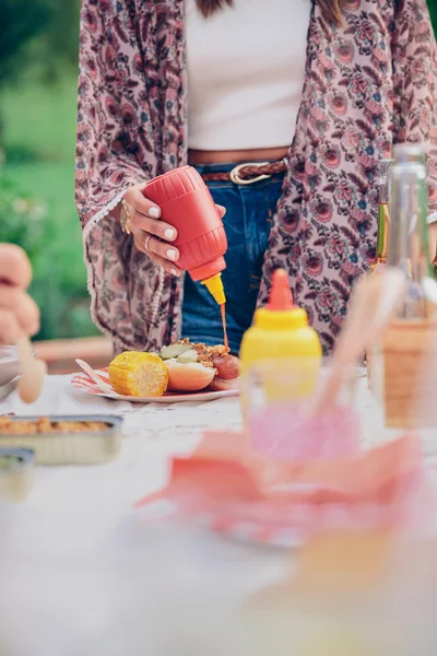 女人的手浇注番茄酱在美国的热狗 — 图库照片
