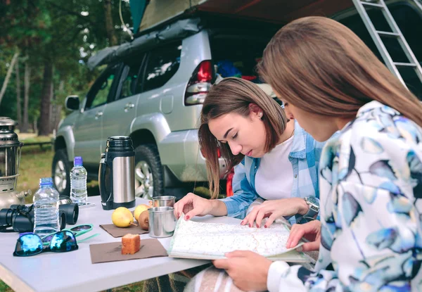 Jovens mulheres procurando roteiro com 4x4 em segundo plano — Fotografia de Stock