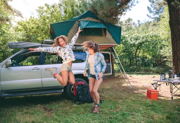 Jovens mulheres se divertindo no acampamento com 4x4 em segundo plano — Fotografia de Stock