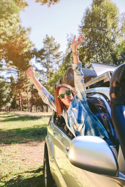 Mulher feliz levantando os braços através do carro da janela — Fotografia de Stock